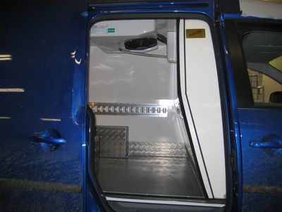 Öppen sidodörr på en transportbil där man kan se installationen av ett kylaggregat i taket